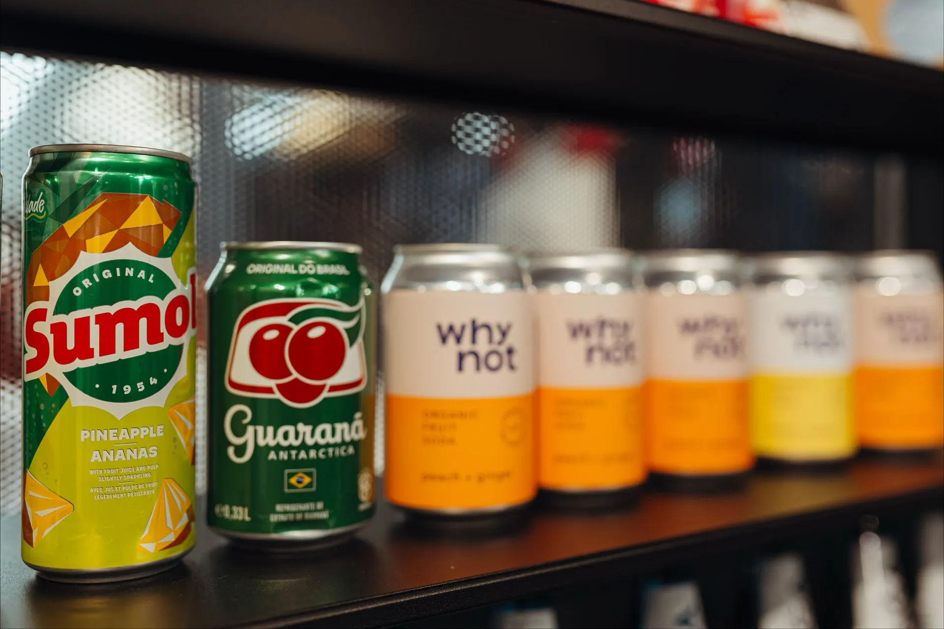 Puszki portugalskich napojów na półce: ananasowy Sumol, Guaraná Antarctica i kilka puszek napoju „why not”